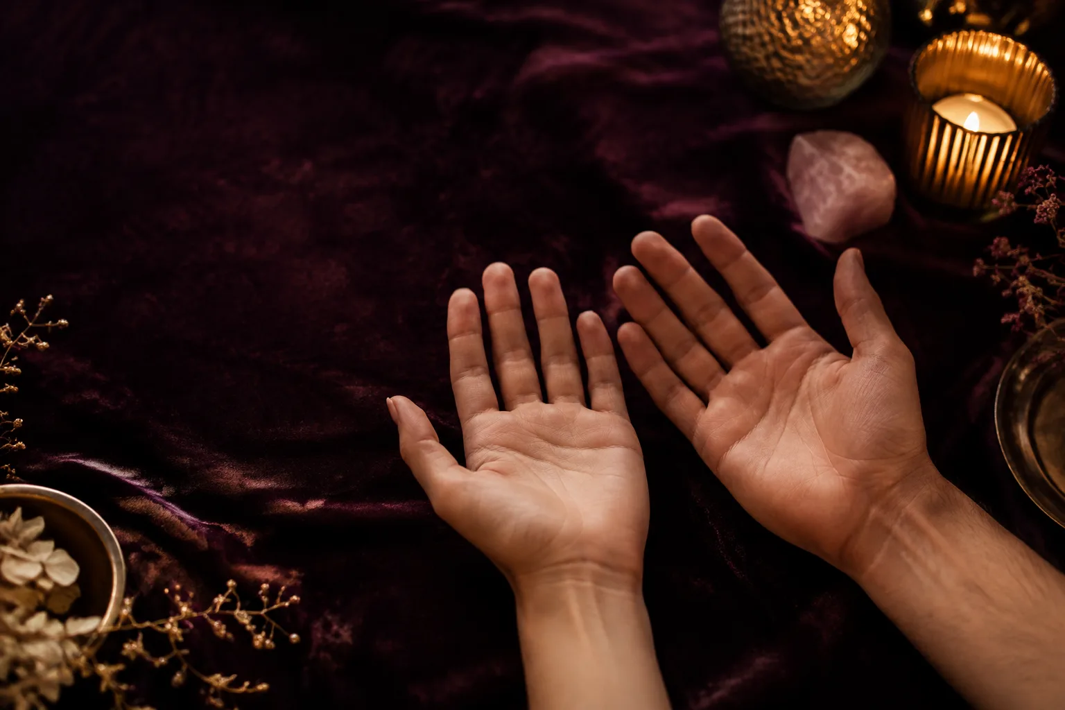 Two open palms resting side by side on deep plum fabric for a love palm reading